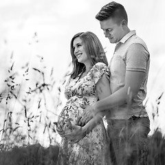 Image showing Young happy pregnant couple hugging in nature.