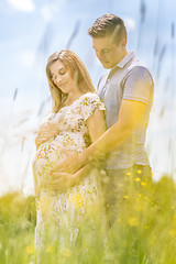 Image showing Young happy pregnant couple hugging in nature.