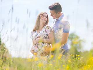 Image showing Young happy pregnant couple hugging in nature.