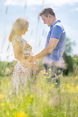 Image showing Young happy pregnant couple hugging in nature.