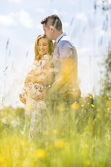 Image showing Young happy pregnant couple hugging in nature.