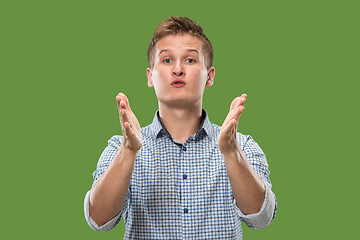 Image showing Beautiful male half-length portrait isolated on green studio backgroud. The young emotional surprised man