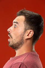 Image showing The young attractive man looking suprised isolated on red