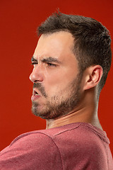 Image showing The young emotional angry man screaming on red studio background