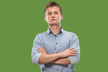 Image showing The serious businessman standing and looking at camera against green background.