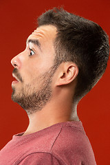 Image showing The young attractive man looking suprised isolated on red