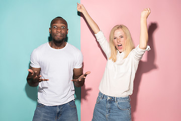 Image showing We won. Winning success happy afro man and woman celebrating being a winner. Dynamic image of caucasian female and male model on pink studio.