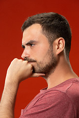 Image showing Beautiful man looking suprised and bewildered isolated on red