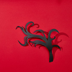 Image showing Creative greeting card handcraft from paper in the form of a branch on a red background with reflection of shadows and copy space for text. Flat lay