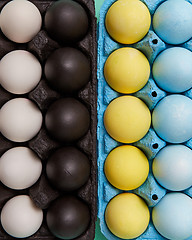 Image showing Set of colorful painted yellow, blue, black and white eggs in different cardboard boxes. Easter background. Flat lay