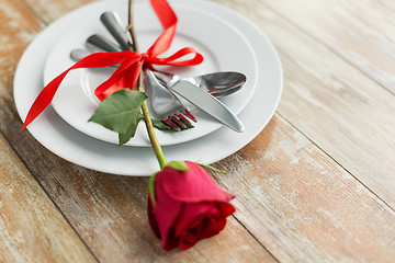 Image showing close up of red rose flower on set of dishes