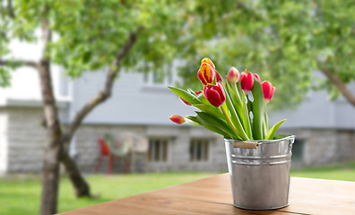 Image showing red tulip flowers on table over summer garden