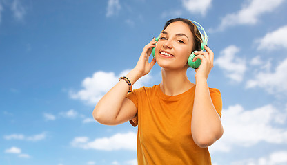 Image showing teenage girl in earphones over sky