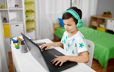 Image showing boy in headphones playing video game on laptop