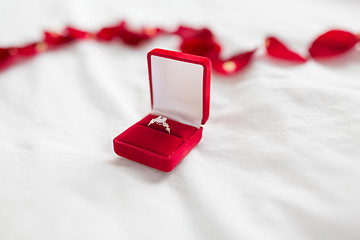 Image showing diamond ring in red velvet gift box on bed sheet