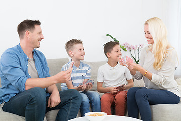 Image showing Happy young family playing card game at home.