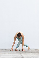 Image showing Fit sporty active girl in fashion sportswear doing yoga fitness exercise in front of gray wall, outdoor sports, urban style