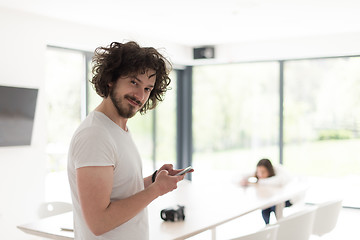 Image showing young man using a mobile phone  at home