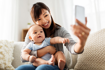 Image showing happy mother with baby son taking selfie at home