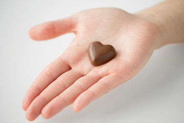 Image showing close up of hand with heart shaped chocolate candy