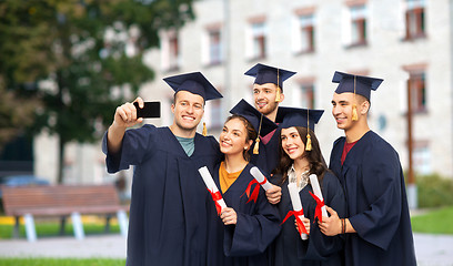 Image showing graduates with diplomas taking selfie by cellphone