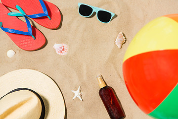 Image showing hat, flip flops and shades and beach ball on sand