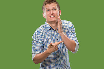 Image showing The young man whispering a secret behind her hand over green background