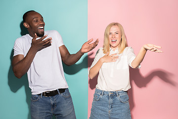 Image showing happy afro man and woman. Dynamic image of caucasian female and afro male model on pink studio.