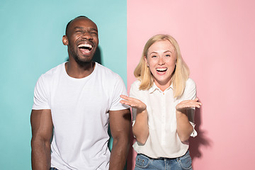 Image showing happy afro man and woman. Dynamic image of caucasian female and afro male model on pink studio.