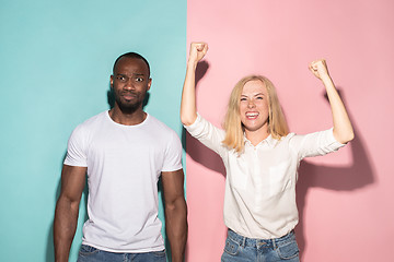 Image showing We won. Winning success happy afro man and woman celebrating being a winner. Dynamic image of caucasian female and male model on pink studio.