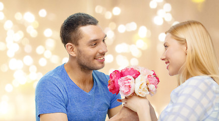 Image showing man giving woman flowers over festive lights