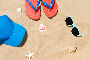 Image showing cap, flip flops, shades and on shells beach sand