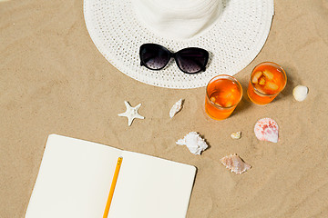 Image showing notebook, cocktails, hat and shades on beach sand