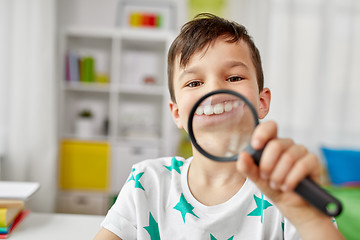 Image showing boy with magnifier showing big teeth at home