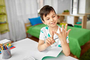 Image showing boy doing homework and counting using fingers