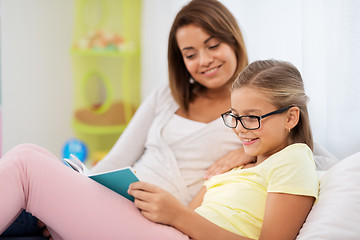 Image showing happy girl with mother reading book at home