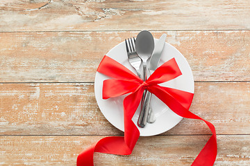 Image showing cutlery tied with red ribbon on set of plates