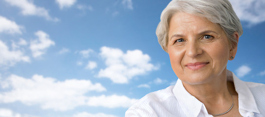 Image showing portrait of smiling senior woman over blue sky