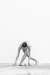 Image showing Fit sporty active girl in fashion sportswear doing yoga fitness exercise in front of gray wall, outdoor sports, urban style. Black and white photo.