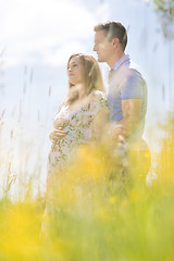 Image showing Young happy pregnant couple hugging in nature.