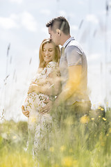 Image showing Young happy pregnant couple hugging in nature.