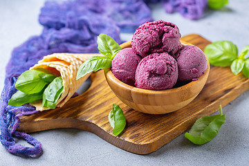 Image showing Blueberry ice cream balls and green basil in a wooden bowl.