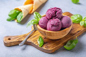 Image showing Blueberry ice cream balls and green basil in a wooden bowl.