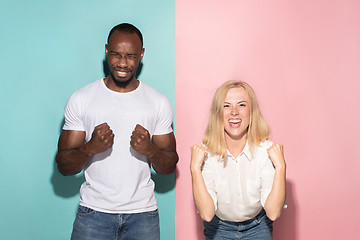 Image showing We won. Winning success happy afro man and woman celebrating being a winner. Dynamic image of caucasian female and male model on pink studio.