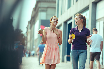 Image showing Beautiful girls holding paper coffee cup and enjoying the walk in the city