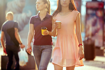 Image showing Beautiful girls holding paper coffee cup and enjoying the walk in the city