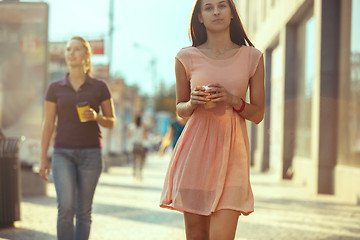 Image showing Beautiful woman holding paper coffee cup and enjoying the walk in the city