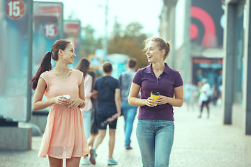 Image showing Beautiful girls holding paper coffee cup and enjoying the walk in the city