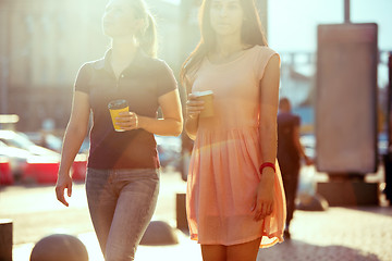 Image showing Beautiful girls holding paper coffee cup and enjoying the walk in the city