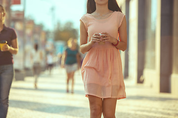 Image showing Beautiful woman holding paper coffee cup and enjoying the walk in the city